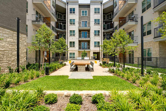 A courtyard with a bench and a fence in front of apartment buildings.