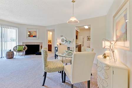 A living room with a wooden table and white couches. at Fox Hollow Apartment Homes, High Point, NC, 27265