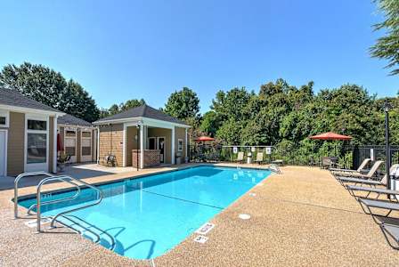 A swimming pool surrounded by trees and chairs. at Fox Hollow Apartment Homes, High Point, NC, 27265