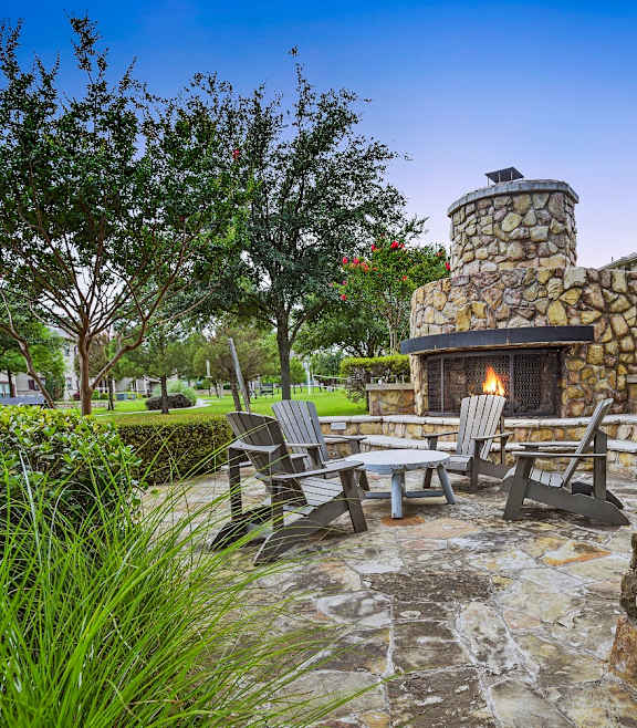 a patio with a stone fireplace and a table and chairs