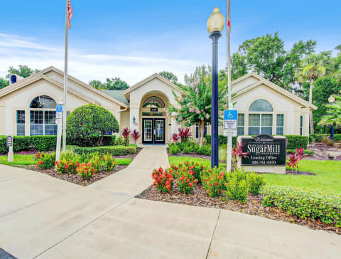 Clubhouse Entrance surrounded by shrubbery and trees with monument sign in front of it