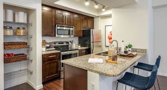 A kitchen with a granite countertop and a black chair.