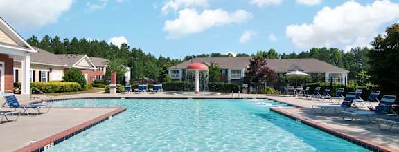 Swimming Pool and Sun Deck with Lounge Chairs with Trees and Building Exteriors in the Background