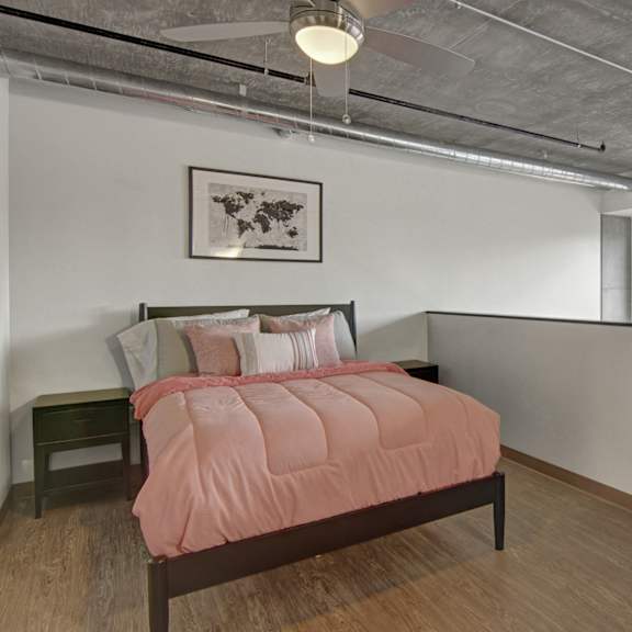 A bedroom at Proxy 333 with a bedside table and a bed with a pink bedspread. 