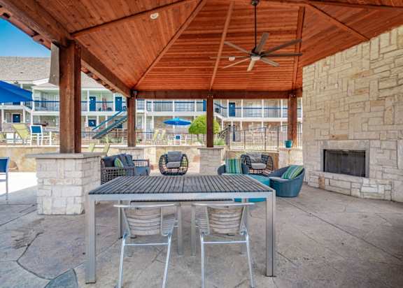 A patio with a table and chairs under a wooden roof. at Aero White Rock, Texas, 75238