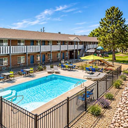 A pool surrounded by a black fence and a building in the background.