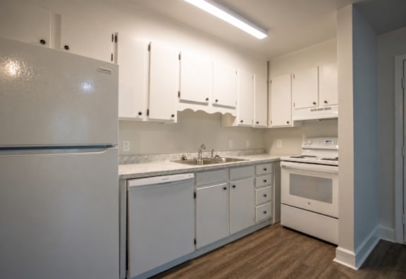 A white kitchen with a refrigerator, sink, and oven.
