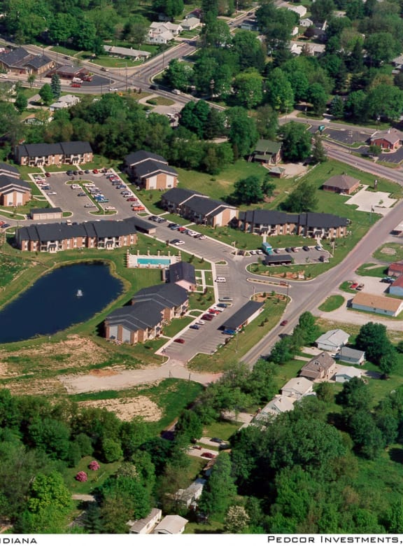 a pond with a fountain in front of a row of houses
