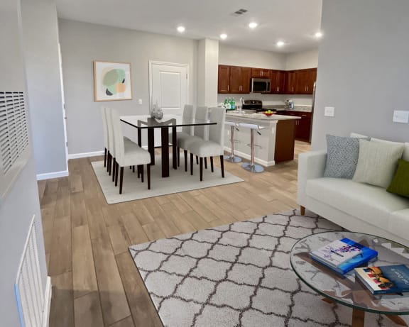 a living room with a couch a table and chairs and a kitchen in the background