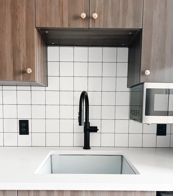 a white kitchen with a sink and a black faucet