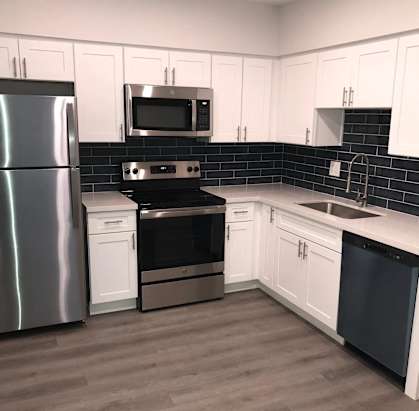 A kitchen with a refrigerator, oven, microwave, and sink.