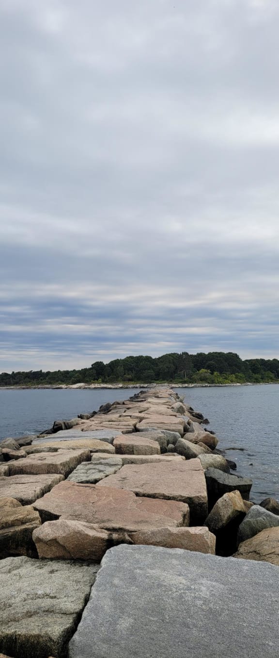 a wall of rocks next to a body of water
