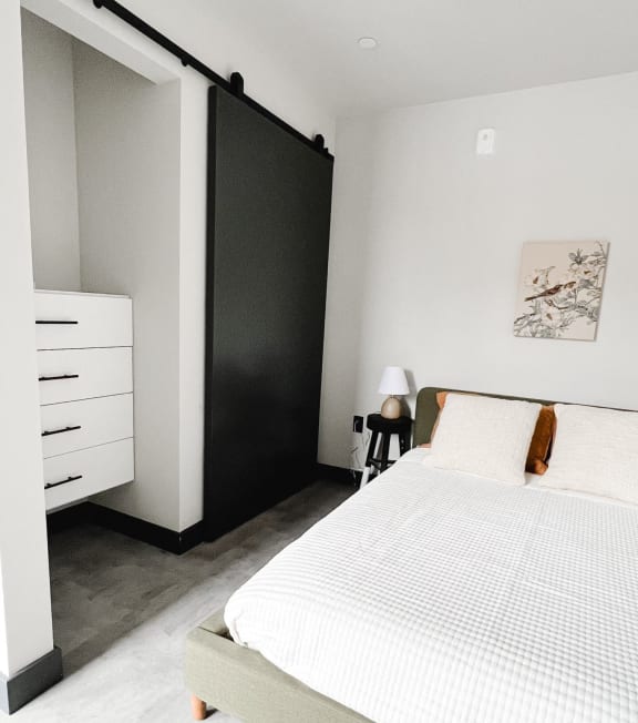 a bedroom with a white bed and a black closet