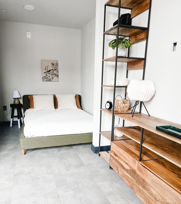 a bedroom with a bed and a shelving unit next to it