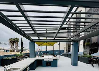 A modern outdoor kitchen with a long counter and a sink.