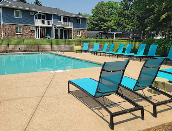 A swimming pool with a diving board and a building in the background.