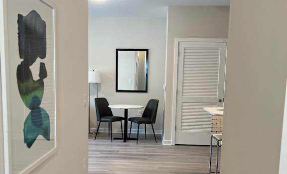 A hallway with a chair and a table in the distance.