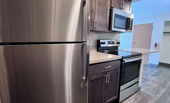 A modern kitchen with a stainless steel refrigerator and wooden cabinets.