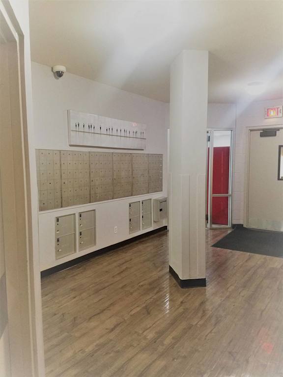 a hallway with white walls and wooden floors and lockers