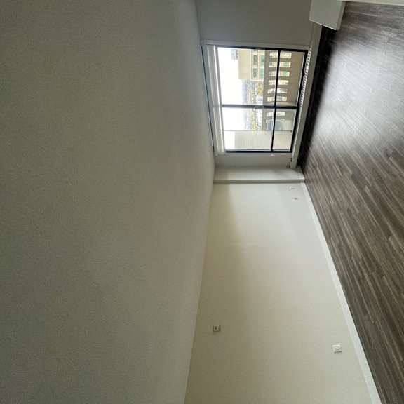 an empty living room with wood flooring and a window