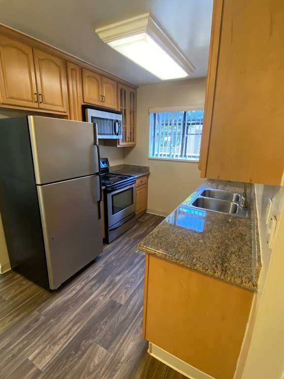 A kitchen with a black counter top and wooden cabinets.