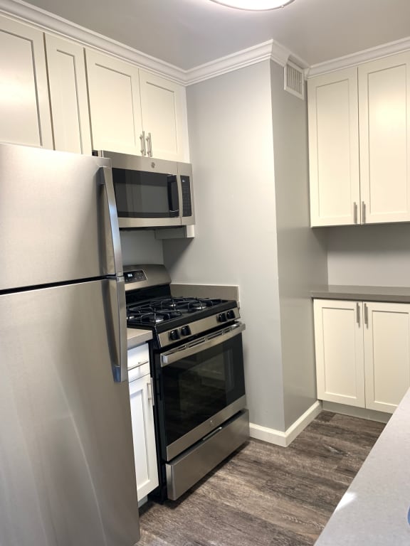 a kitchen with white cabinets and a counter top with an oven and a sink