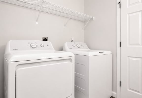 Two white front loading washing machines in a laundry room.