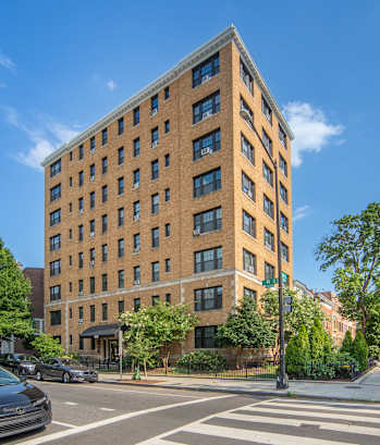 A tall brick building with a green sign on the front.