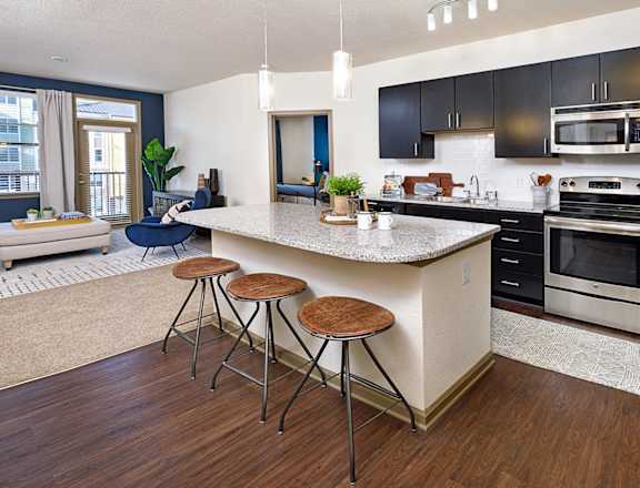 spacious kitchen with island and stools at the district flats apartments