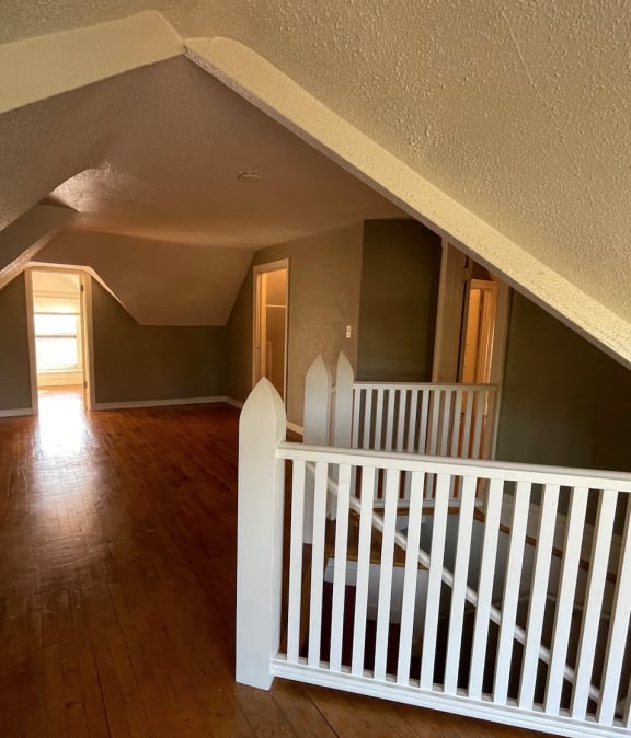 a view from the top of the stairs looking into the living room and dining room