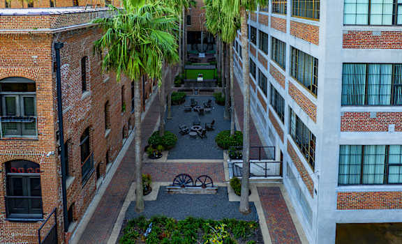 A courtyard surrounded by brick buildings with a fence and a tree.