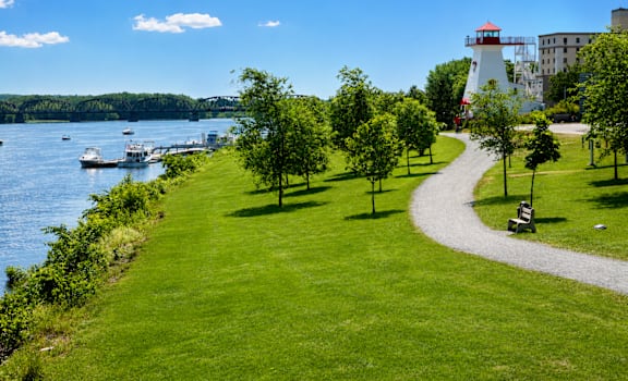 A lighthouse stands on a grassy area next to a body of water.