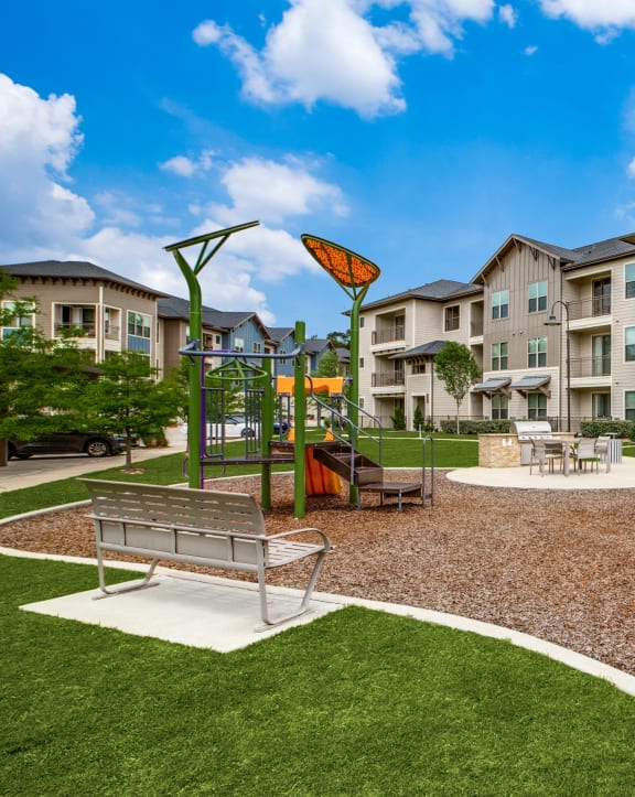 an outdoor play area with a playground and benches in front of an apartment building