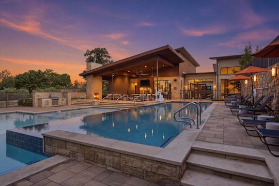 a swimming pool with lounge chairs and a building with a stone wall