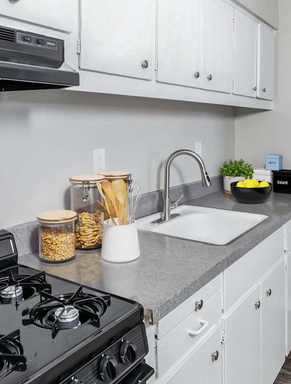 A kitchen with a black stove top and white cabinets.