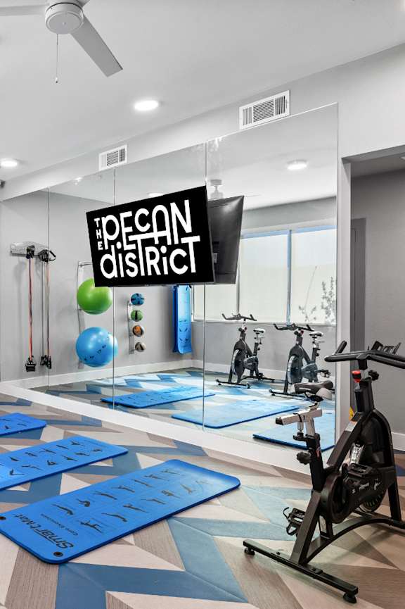 A gym with exercise equipment and a sign that says "Pecan District".
