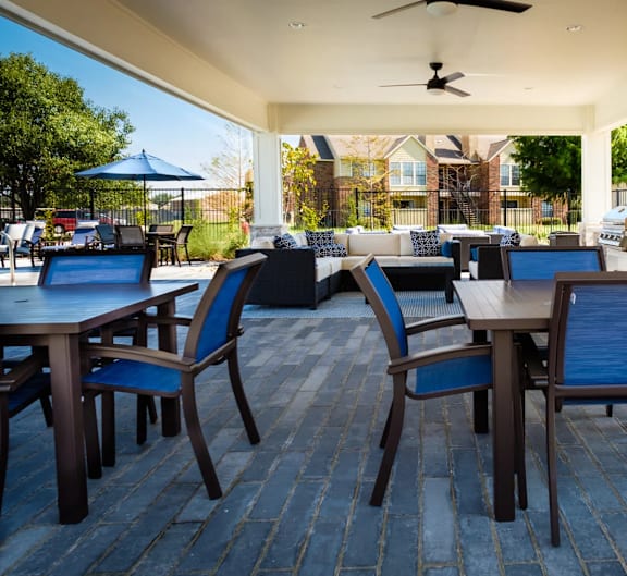 A patio with tables and chairs and a ceiling fan.