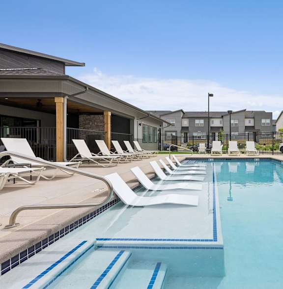 A pool surrounded by a black fence and a small patio area.