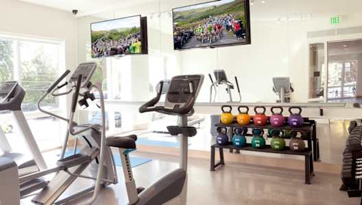 Coze Flats fitness center with a treadmill, elliptical, spin bike, free weights and kettle bells