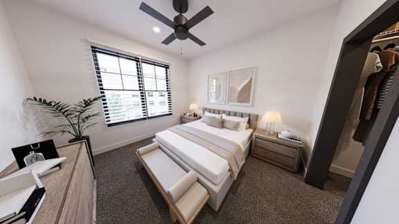 A bedroom with a large bed, a ceiling fan, and a window with blinds.