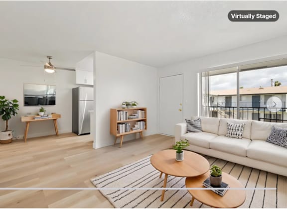 A modern living room with a white sofa, a wooden coffee table, and a large window.
