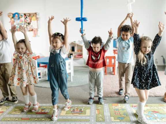 A group of children are playing with a cross in a room.