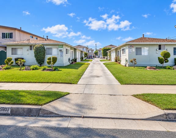 A residential street with houses on both sides and a clear blue sky above.