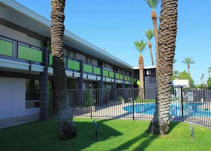 A building with a pool and palm trees in front.