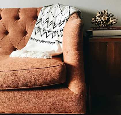 A brown chair with a white and black throw blanket draped over it.