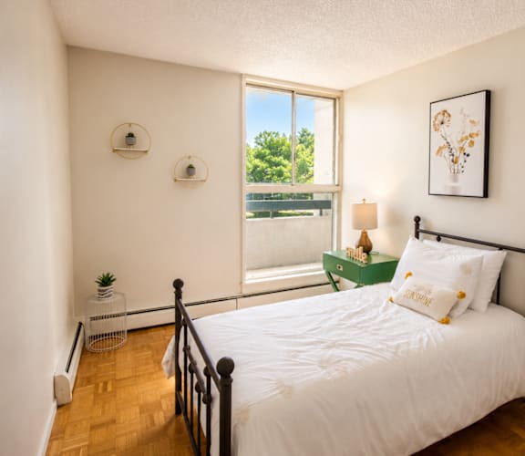 A bedroom with a large bed and a window overlooking a green area.