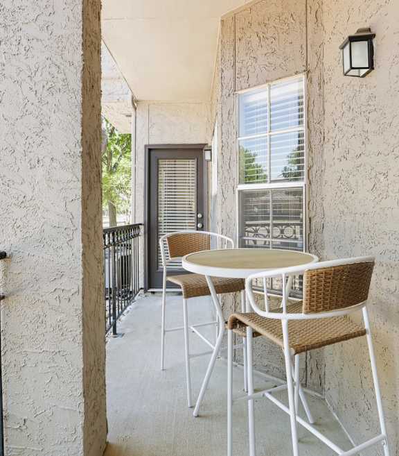 a balcony with a table and chairs and a tree in the background