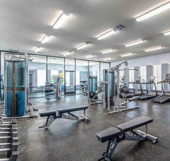 a gym with cardio equipment and glass walls