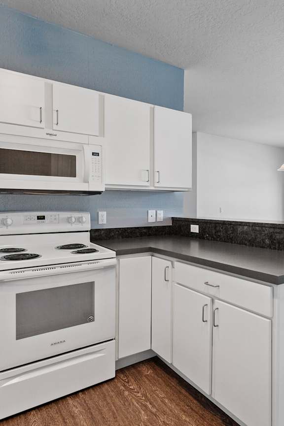 A kitchen with white appliances and cabinets.