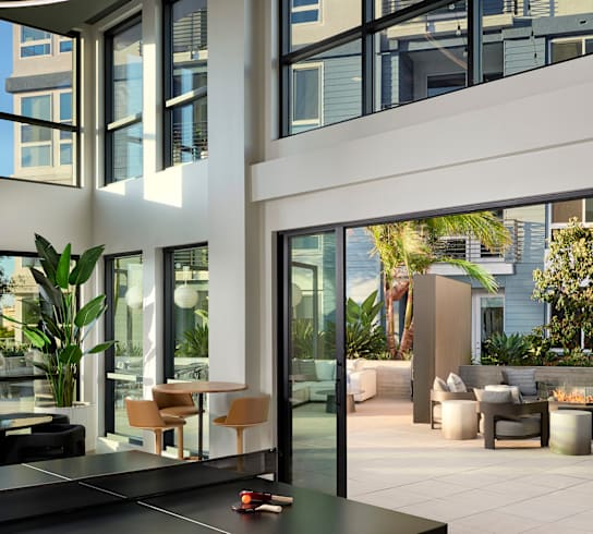 A ping pong table is in the middle of a spacious room with a lot of windows.